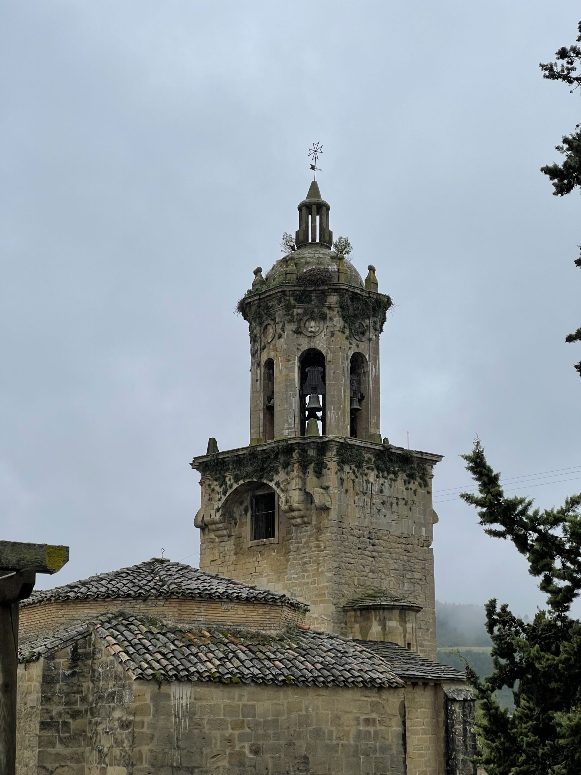 Il campanile di una chiesa a Puente La Reina. Davanti all’alberello di sinistra c’è una cicogna.